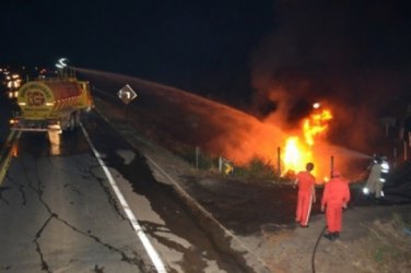 Carreta carregada de combustível pega fogo ao tombar na curva da morte