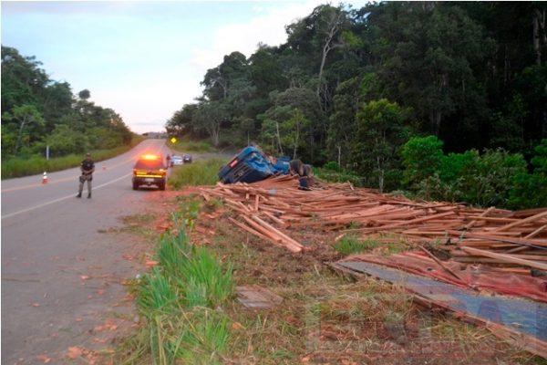 Caminhão carregado com madeira tomba em curva da BR-435 deixando pai e filho feridos