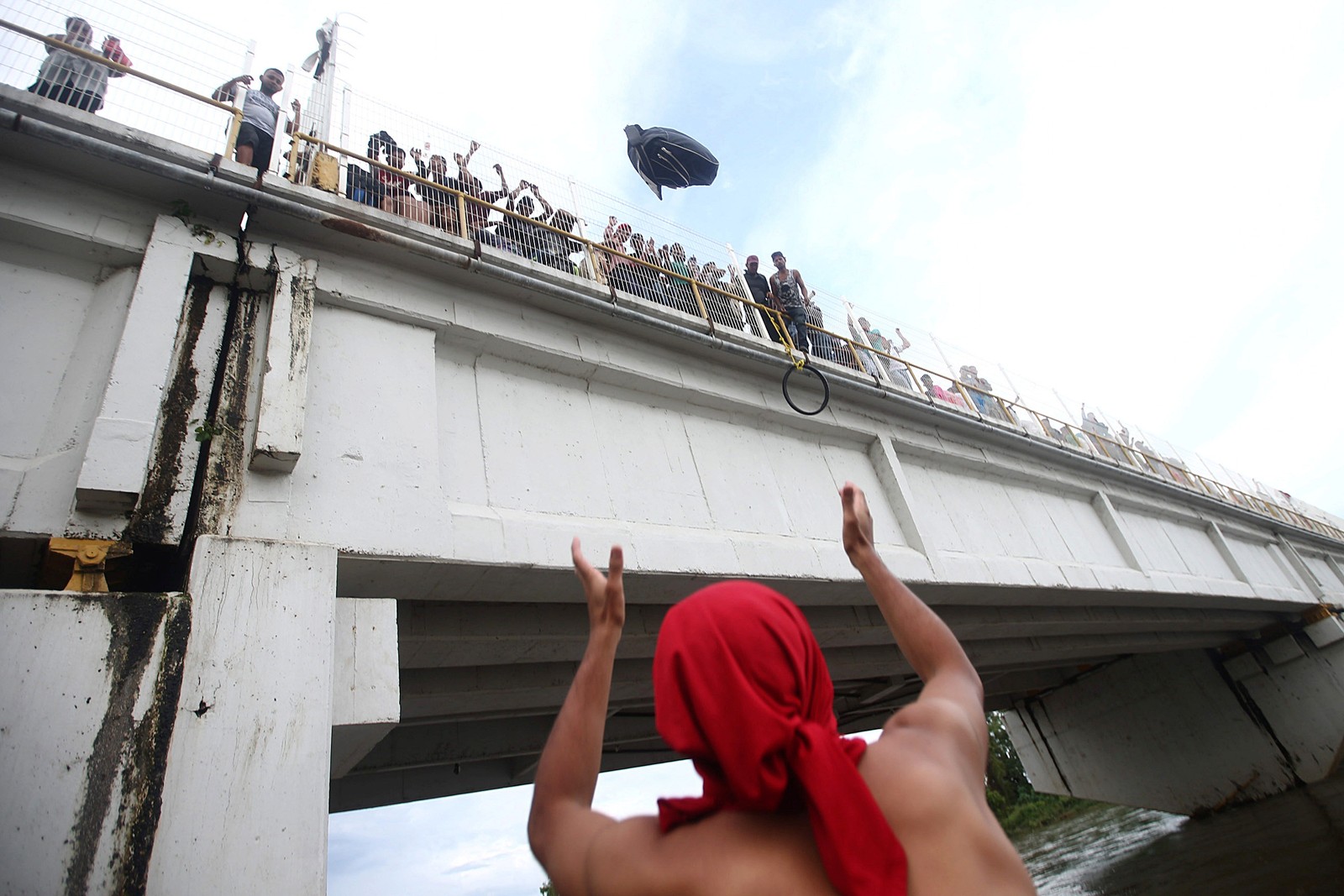 Migrante joga uma mochila da ponte que liga o México e Guatemala para evitar fronteira — Foto: REUTERS/Edgard Garrido